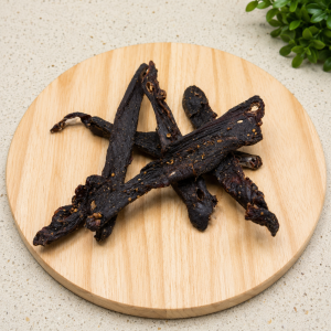 Kudu chilli bites – spicy South African kudu game biltong sticks on a wooden board
